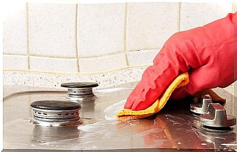 Woman cleaning the stove with a kitchen towel